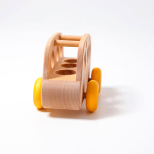 A wooden natural bus with yellow wheels. Front view. There are three spots in the bus for peg people to ride in it