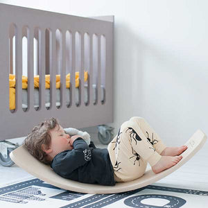 Boy laying in the wobbel board with his eyes closed, sucking his stuffed animal.