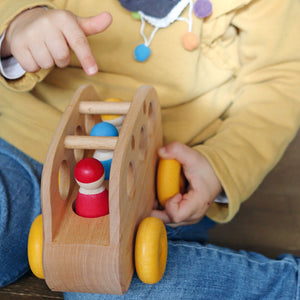 A child playing with the wooden bus and peg people