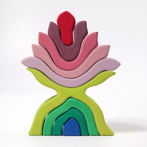 Nine-piece wooden flower sculpture.The five top pieces are in shades of pink and red. The bottom four pieces are in shades of green and blue.