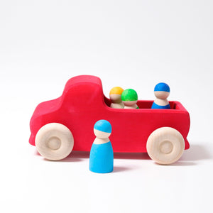 Large wooden truck pained red with natural wheels. Side view with three wooden friends in the trunk/bed.