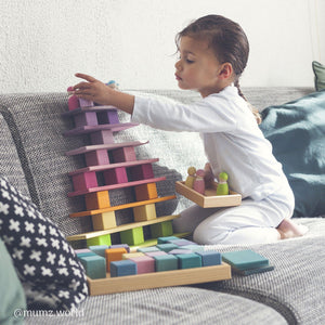 girl sitting on the sofa building with pastel building boards, pastel blocks, and pastel friends