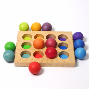 image of three of the small rainbow ball sorted into the corresponding color hole in board.