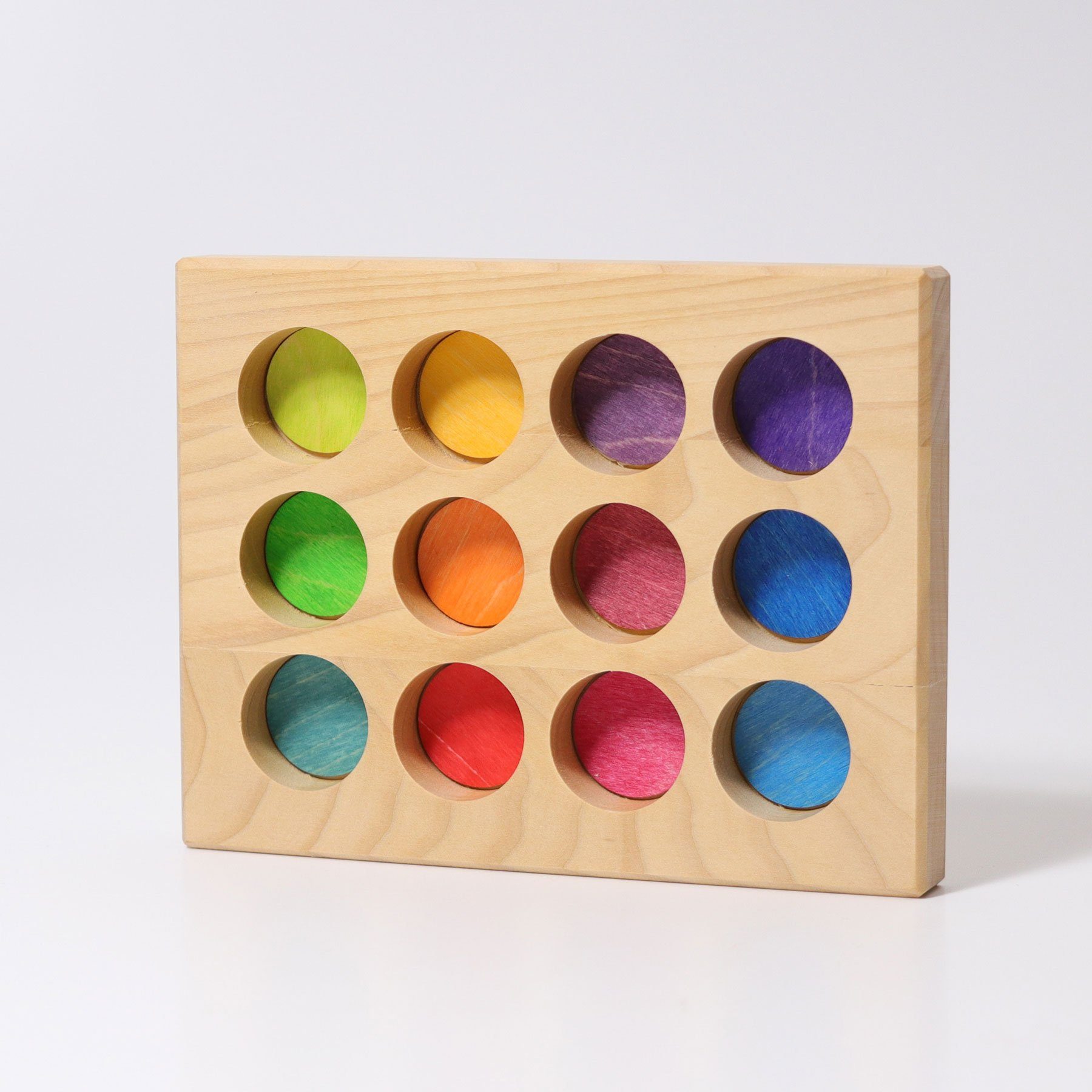 The rainbow sorting board is made from one solid piece of wood with 12 holes removed. Each hole is painted a rainbow color that matched the rainbow friends and small rainbow balls. Colors include: lime green, green, teal, yellow, orange, bright red, dark red, maroon, dark purple, bright purple, royal blue, and baby blue.
