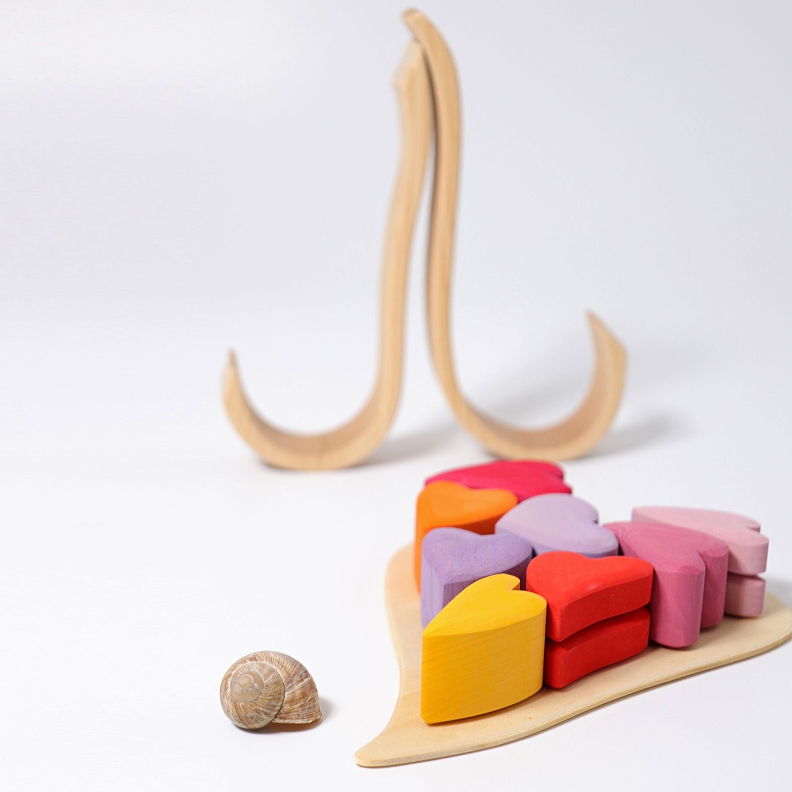 the red hearts set includes 8 different different colors in tints of reds, purples, and yellows. The hearts sit on a heart-shaped wooden frame enclosed by two natural wooden pieces that form a heart.