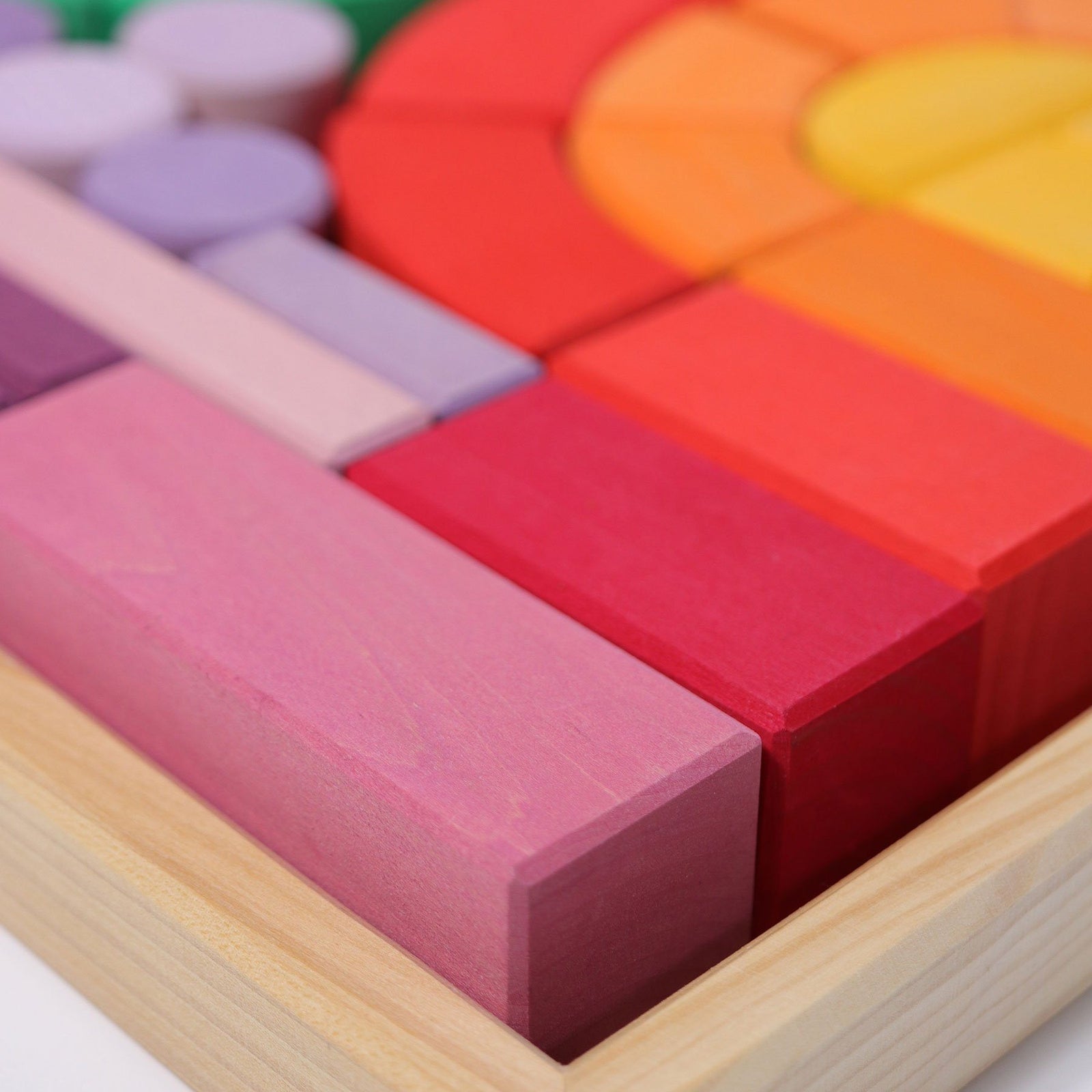 Romanesque building set in frame. Set includes 62 wooden building blocks in rainbow and pastel colors. Shapes range from pillars, rectangular blocks, square blocks, slates, and curved blocks.