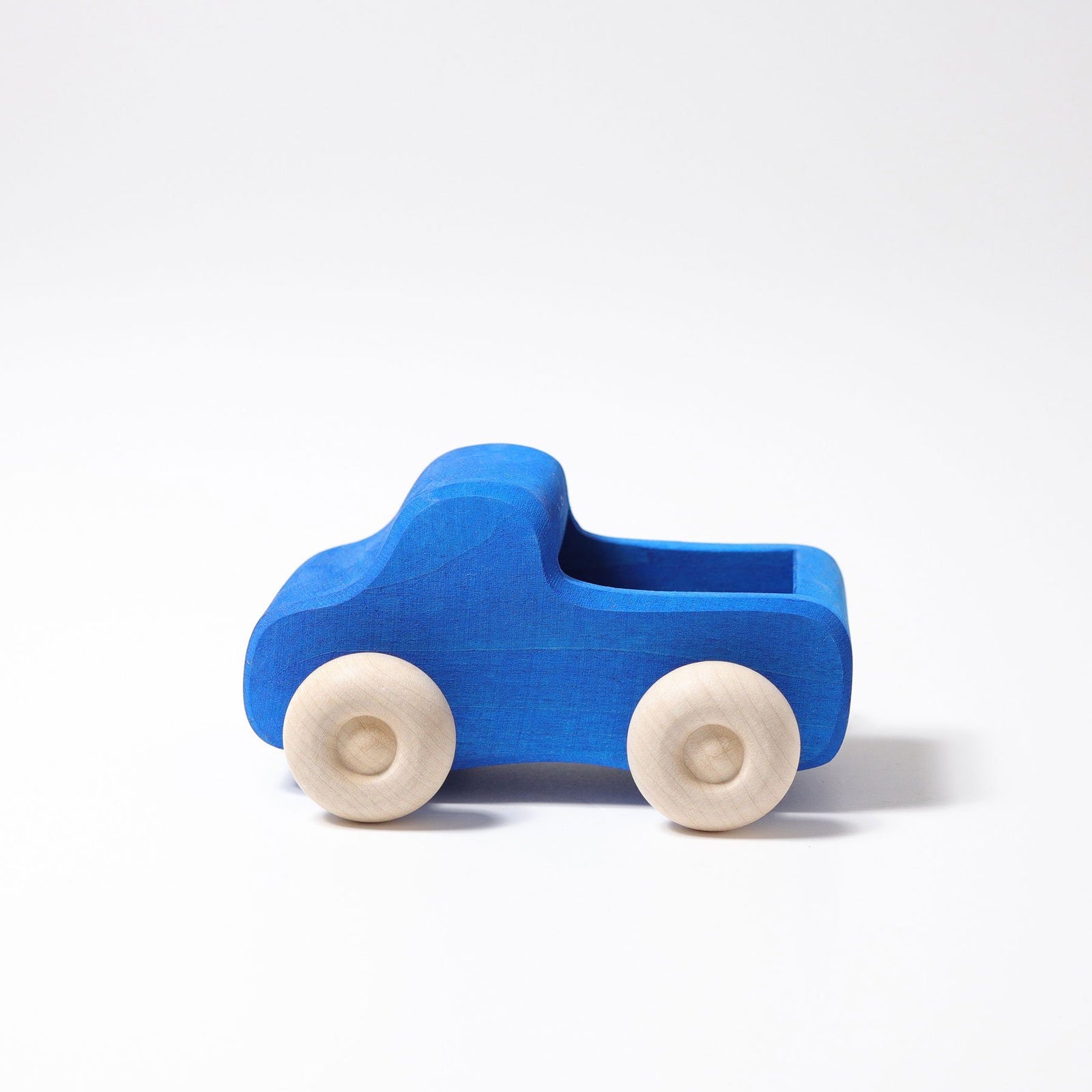 A wooden truck painted blue with natural wheels. Side view.
