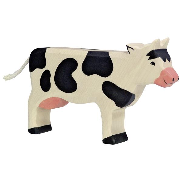 A cow wooden figure painted white with black spots and hooves and a pink nose.