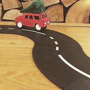 Image showing the track on a hardwood floor while a red truck carrying a Christmas tree driving on it.