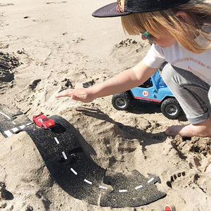 Image of a boy playing with the track in the sand.